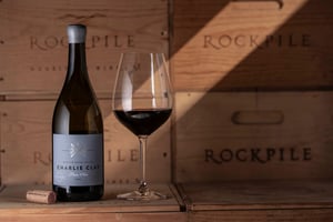 Image of a wine bottle of Charlie Clay Pinot Noir next to a wine glass.