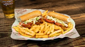 A dish of Shrimp Po Boy hoagie roll sandwich with a serving of french fries.