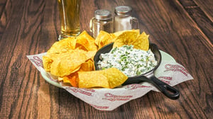 A plate of chips served with spinach artichoke dip.
