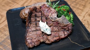 Plater with 18oz T-bone steak served with herb butter, baked potato and natural jus.