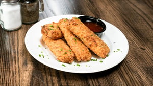 A plate of crab rangoon mozzarella sticks with side of sweet chili sauce.