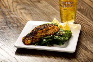 Image of a plate of Pistachio-crusted salmon with drink on the side.