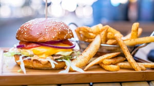 Photo of cheeseburger and french fries sitting on platter next to a pool.