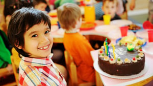 Image of a child birthday party celebration with a chocolate cake.