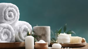 A serene spa setting featuring warm, plush towels, softly glowing candles, and an array of soothing aromatic scents.