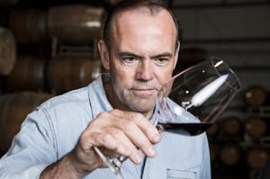 Image of Charlie Palmer visually evaluating a glass of wine for color, clarity, consistency, and effervescence.